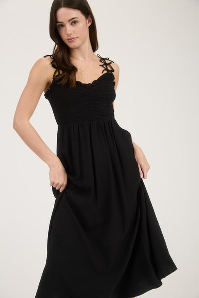 Woman wearing a black sleeveless dress against a white background