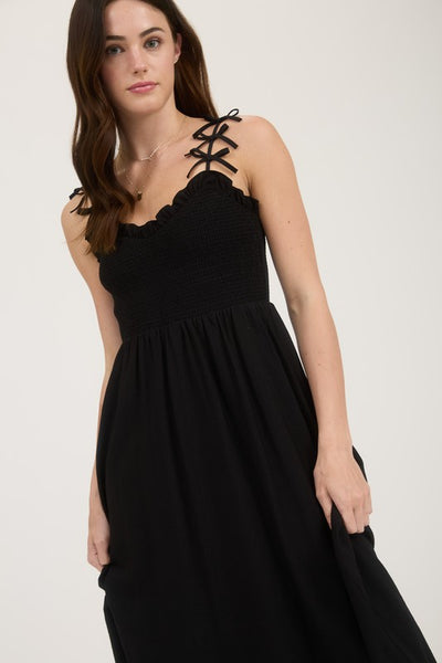 Woman wearing a black dress with lace-up straps on a white background