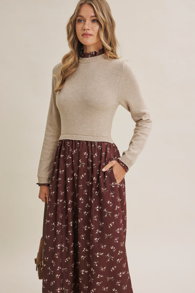 A woman modeling a beige mock-neck long-sleeve knit top paired with a dark brown floral maxi skirt, standing against a plain light beige studio background.