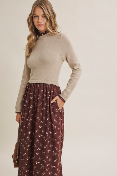 A woman modeling a beige mock-neck long-sleeve knit top paired with a dark brown floral maxi skirt, standing against a plain light beige studio background.