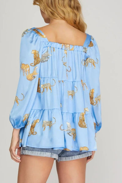 Light blue off-shoulder top with animal print and denim shorts on a plain background