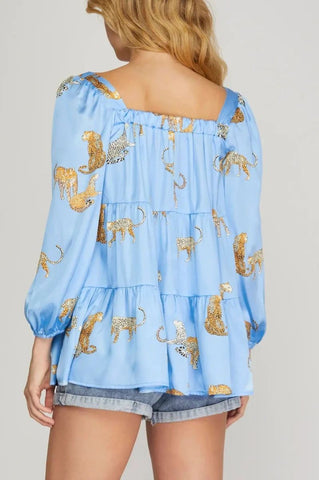Light blue off-shoulder top with animal print and denim shorts on a plain background