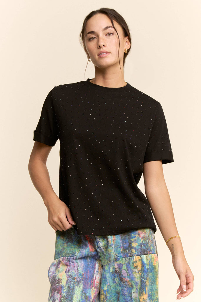 Woman wearing a black t-shirt with colorful pants on a beige background