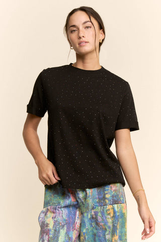 Woman wearing a black t-shirt with colorful pants on a beige background