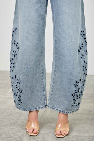 Light blue jeans with floral embroidery on a neutral background