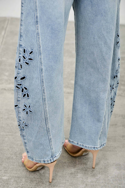 Light blue jeans with floral cut-out details on a neutral background