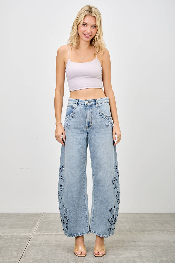 Woman wearing light blue jeans and a white top on a plain background