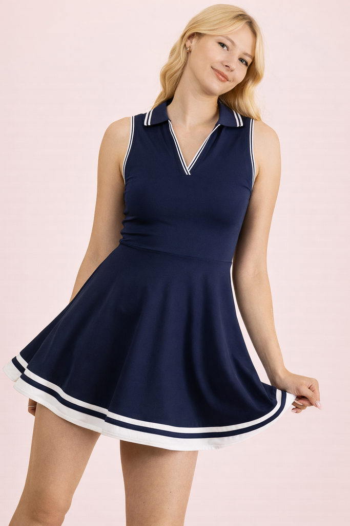 Woman wearing a navy blue dress with white trim on a pink background