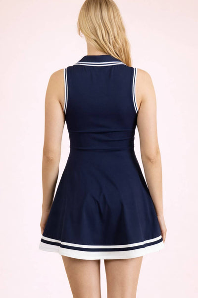 Navy blue dress with white trim on a model against a light pink background