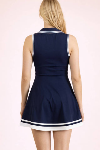 Navy blue dress with white trim on a model against a light pink background