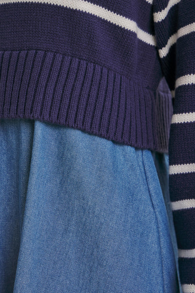 Close-up of a navy blue ribbed knit sweater with white horizontal stripes layered over a blue denim skirt.