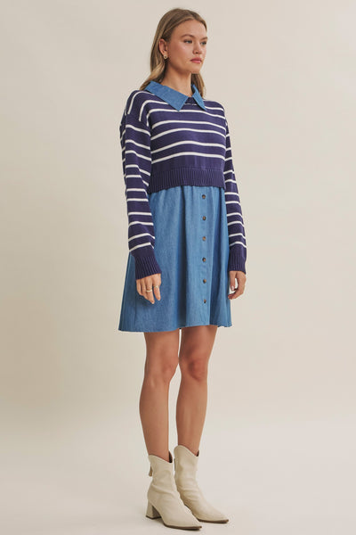 A woman models a two-piece knit and denim set featuring a blue and white striped long-sleeve polo top with a blue collar, paired with a matching blue denim button-front mini skirt, styled with cream-colored ankle boots against a solid beige studio background.