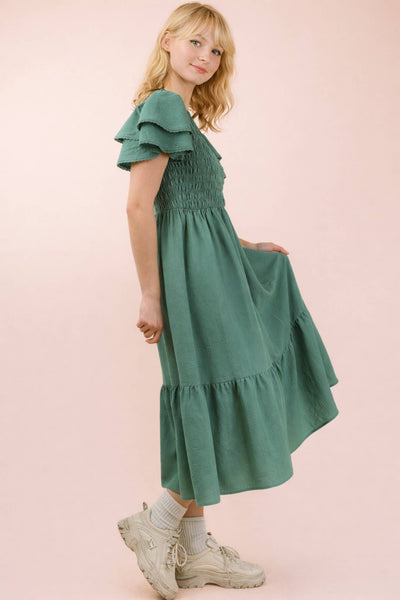 Young girl wearing a green dress on a pink background