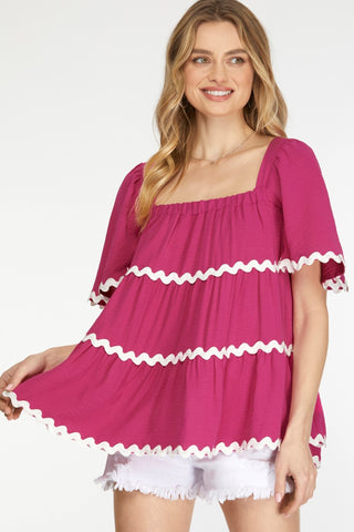 Woman wearing a pink dress with white trim on a white background