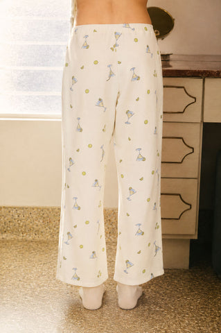 Person wearing white pajama pants with small patterns in a room.