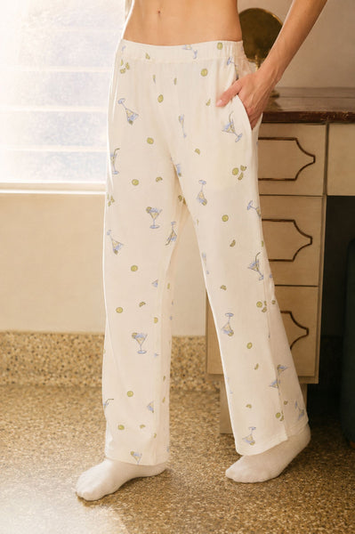 Person wearing white pajama pants with a pattern, standing in a room.