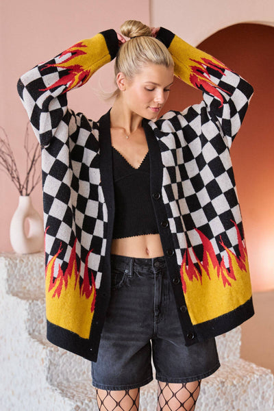 Woman wearing a checkered cardigan with flame patterns in a room with a pink wall.