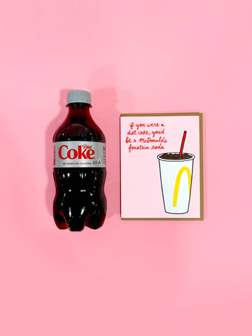 Coke bottle and a framed picture on a pink background