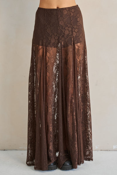 A brown lace maxi skirt with a sheer overlay, shown on a model from the waist down against a neutral beige background.