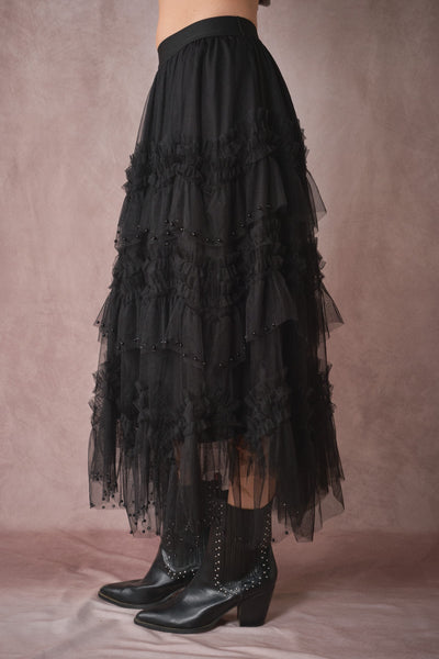 Black tiered skirt with lace details worn by a person on a pink background