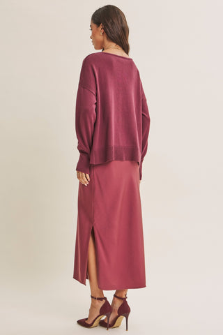 A woman shown from the back wearing a matching dusty rose long-sleeve knit top and midi skirt set, paired with matching heels, against a plain light beige studio background.