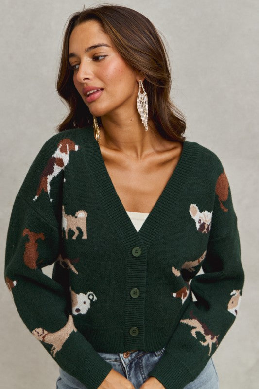 Woman wearing a green cardigan with dog pattern against a gray background