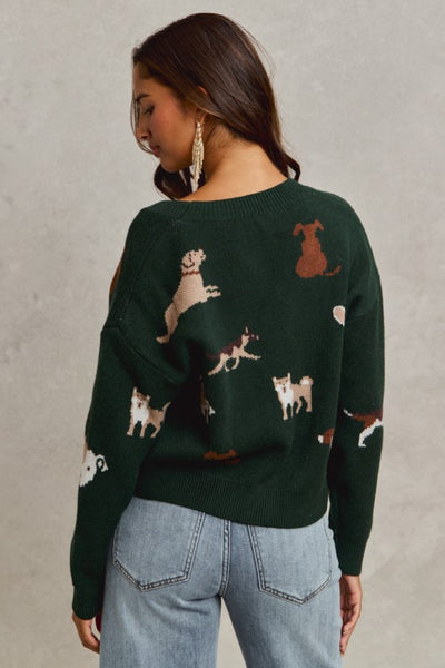 Person wearing a green sweater with dog patterns on a neutral background