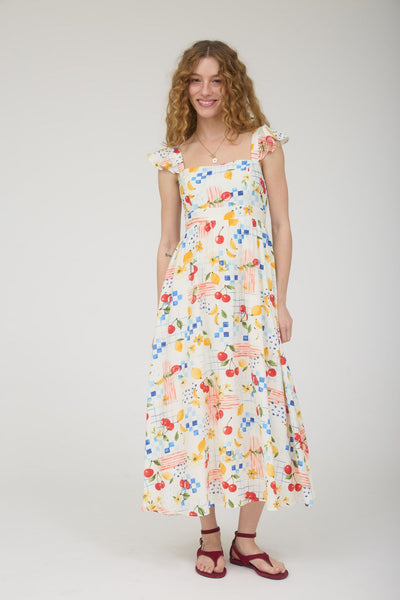 Woman wearing a colorful floral & fruit dress on a white background