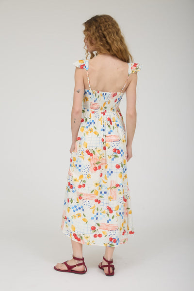 Woman wearing a floral & fruit dress on a plain background