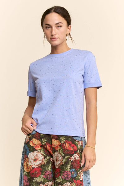 Woman wearing a light blue t-shirt and floral pants on a beige background