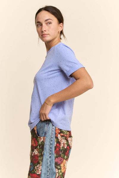 Woman wearing a light blue t-shirt and floral pants on a beige background