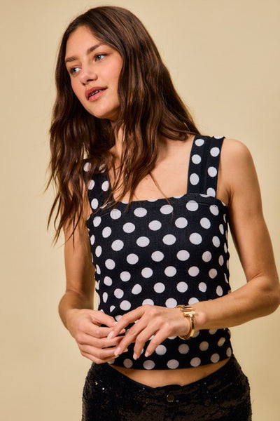 Woman wearing a black polka dot top against a beige background