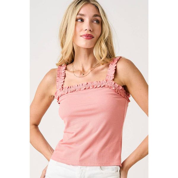 Woman wearing a pink tank top with ruffled straps on a white background