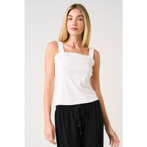 Woman wearing a white tank top and black pants on a plain background