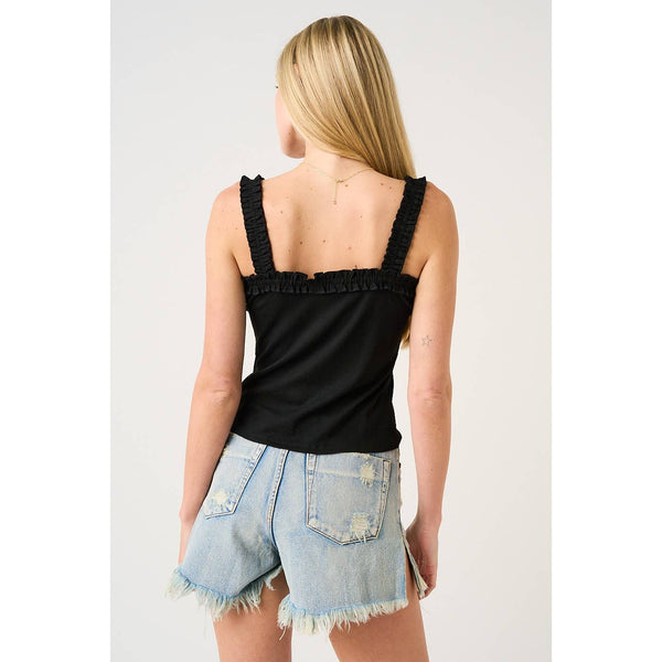 Person wearing a black tank top and denim shorts on a plain background