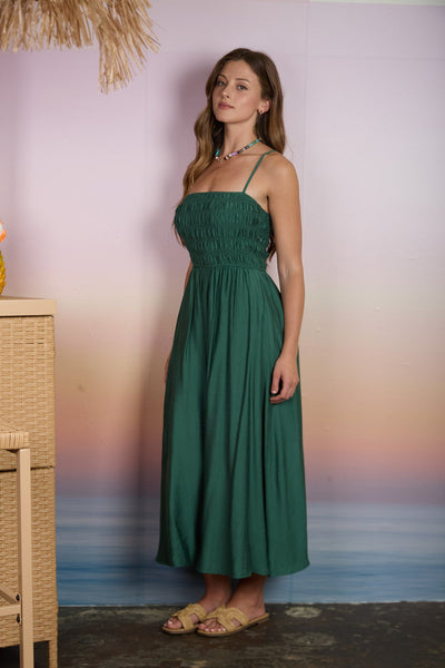 Woman wearing a green dress standing against a blurred background