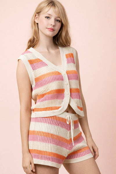 Woman wearing a colorful knitted vest and shorts set on a pink background