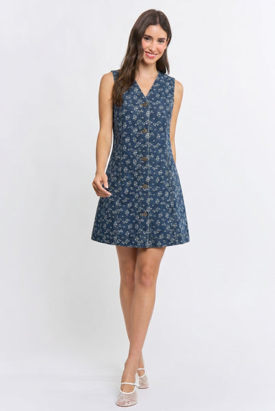 A woman modeling a sleeveless, button-front A-line dress with a blue and white floral pattern, photographed against a plain light gray studio background.