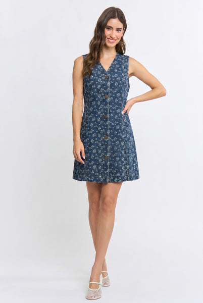 A woman modeling a sleeveless, button-front A-line dress with a blue and white floral pattern, set against a plain white studio background.