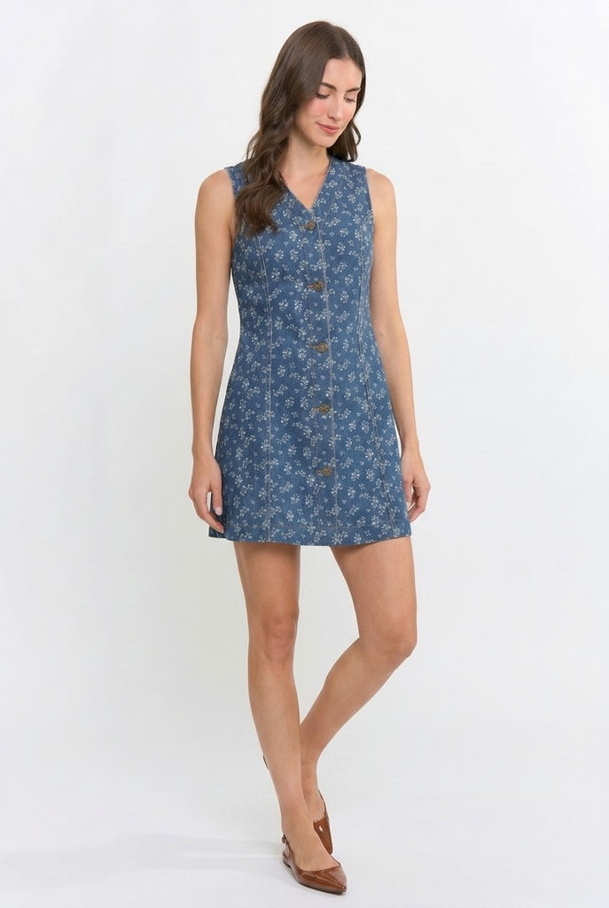 A woman modeling a sleeveless blue mini dress with a small floral pattern and a button-up front, set against a plain white studio background.