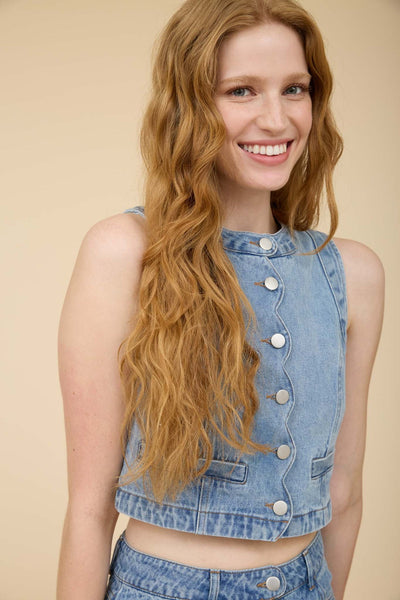 Woman wearing a sleeveless scalloped button-front denim vest top made from 100% cotton with a matching denim mini skirt.