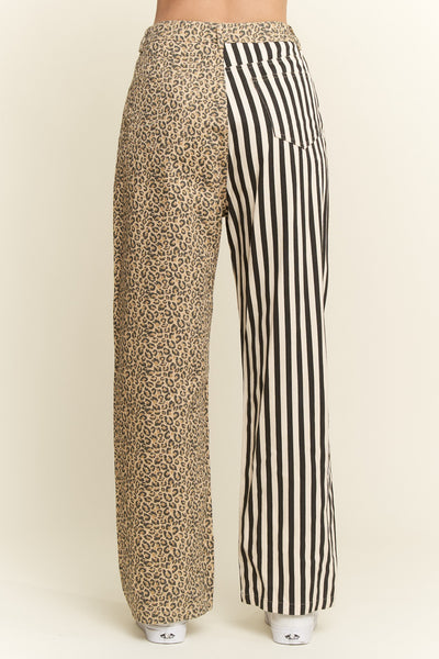 A pair of wide-leg pants shown from the back, featuring a mixed print design: one leg has a beige and brown leopard print, and the other leg has black and white vertical stripes.