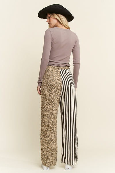 Woman wearing a brown long-sleeve top and patterned pants on a beige background