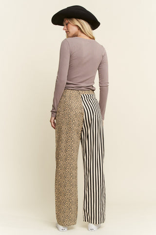 Woman wearing a brown long-sleeve top and patterned pants on a beige background