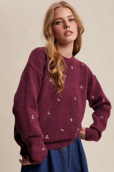 Woman wearing a maroon sweater with small white patterns on a beige background