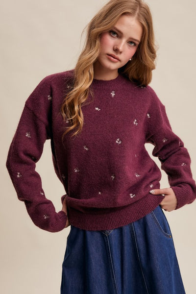 Woman wearing a burgundy sweater with small white patterns on a beige background