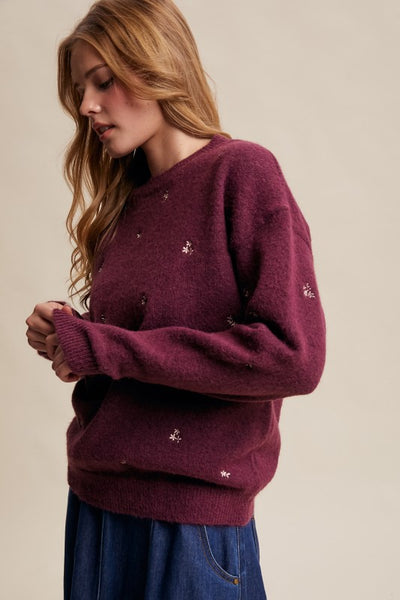 Woman wearing a burgundy sweater with small white patterns on a beige background