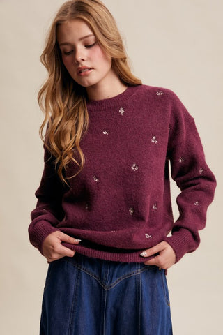 Woman wearing a burgundy sweater with small patterns on a beige background