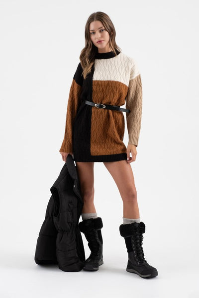 Woman wearing a two-tone sweater dress with black boots on a white background