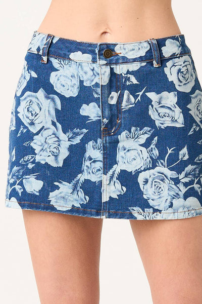 Blue denim skirt with white floral pattern worn by a person on a plain background